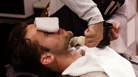 man getting his beard shaved with shaving brush