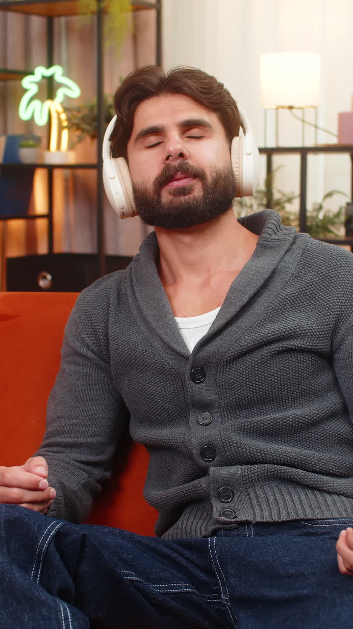 Indian man wears wireless headphones listens nature sound meditates calm smiles gives approval sign