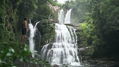 man looks around with nauyaca waterfalls costa rica rain forest in background