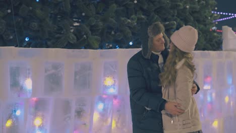 happy couple kisses at beautiful christmas tree on square