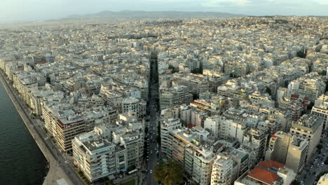 Filmische-Drohnen-Luftaufnahmen,-Die-Bei-Sonnenuntergang-über-Die-Nordgriechische-Stadt-Thessaloniki-Fliegen-Und-Einer-Hauptstraße-In-4k-Folgen