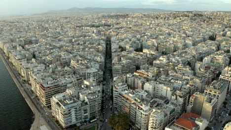 cinematic drone aerial footage flying over the northern greece city of thessaloniki at sunset following a main road in 4k