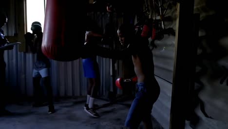 Male-boxers-practicing-boxing-with-punching-bag-4k