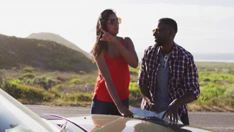 african american couple using maps for directions while standing near convertible car on road
