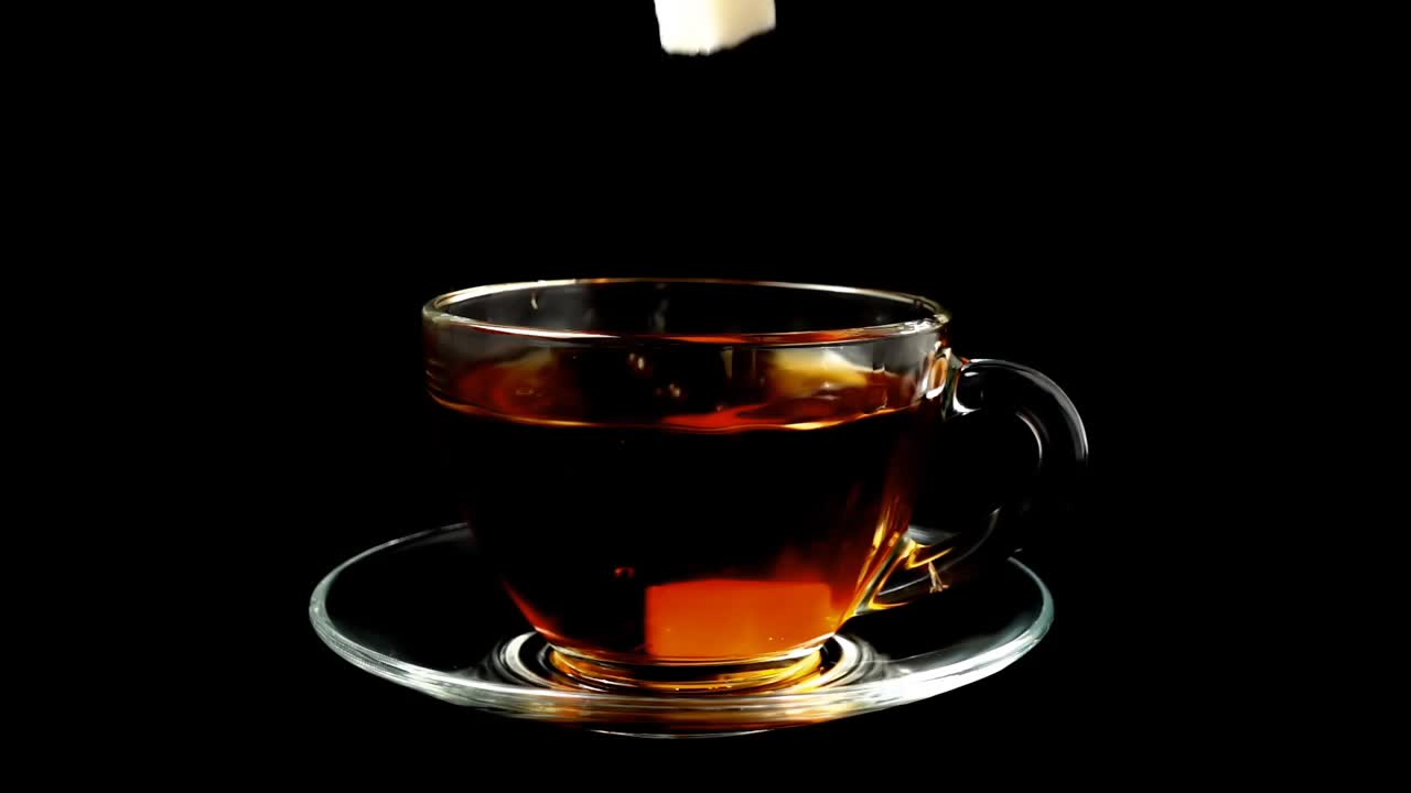 Zucchero cade in una tazza con tè. Movimento rallentato.