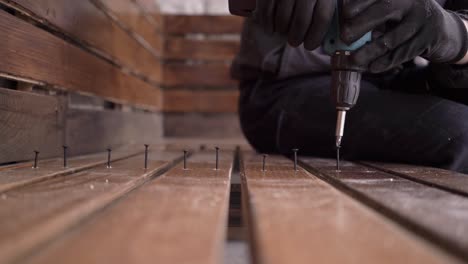 el hombre atornilla los tornillos en un banco de madera que él mismo