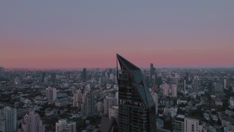 aerial vantage point, bangkok's skyline unfolds, displaying urban life against a backdrop where the horizon takes on post-sunset hues of red and violet