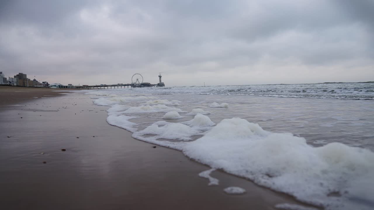 네덜란드의 셰베닌겐 해변에서 흐린 날씨와 작은 거품 파도에서 느린 동영상