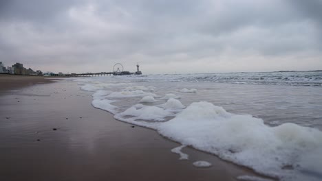 Cámara-Lenta-En-La-Playa-De-Scheveningen,-Países-Bajos,-Durante-El-Tiempo-Nublado-Y-Una-Pequeña-Ola-De-Espuma