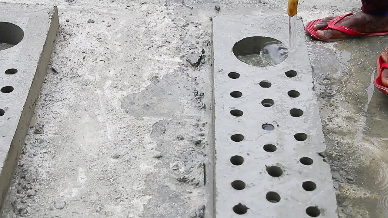 Indian mason worker pouring water on a concrete slab to further harden it as part of the finishing process