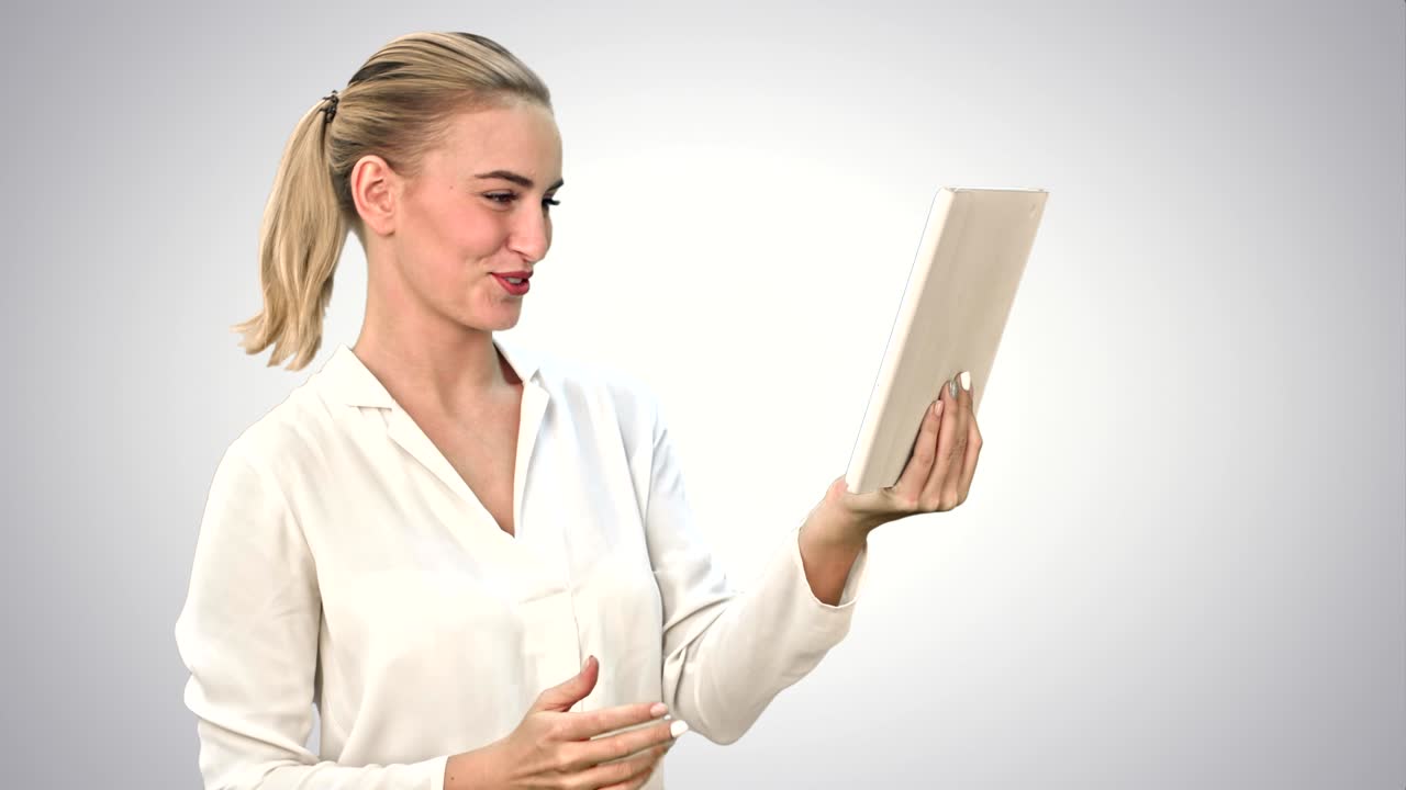 una mujer de negocios positiva está hablando por skype con socios en una tableta sobre un fondo blanco.