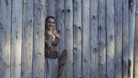 niña vikinga feliz con espada y escudo asomándose por la puerta y escondiéndose