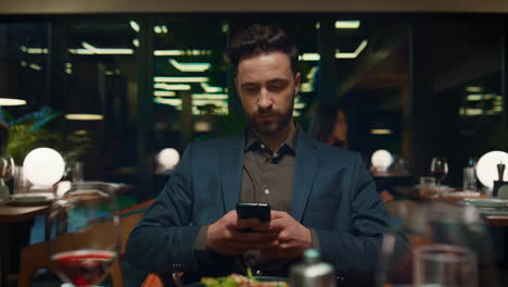 focused businessman sitting restaurant. respectable man texting mobile phone.