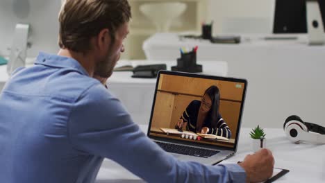 Caucasian-male-teacher-using-laptop-on-video-call-with-female-student,-making-notes