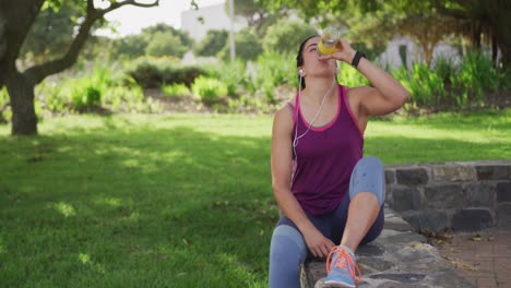 mujer caucásica bebiendo agua en un parque