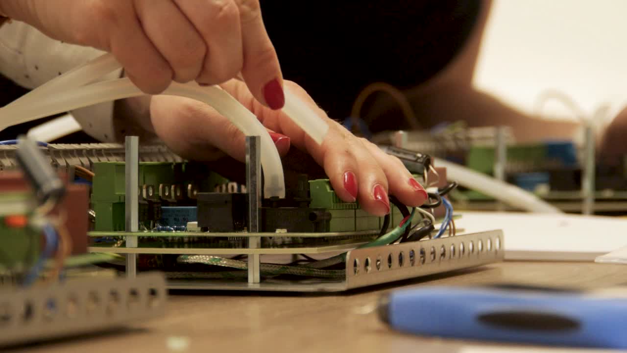 Skilled woman's hands assembling tubes in an electronic production company, showcasing precision and expertise