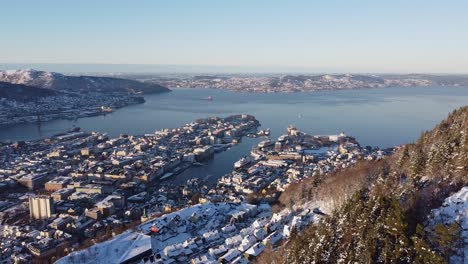 aerial shot over bergen cityscape from hillside mountain with snow - norway