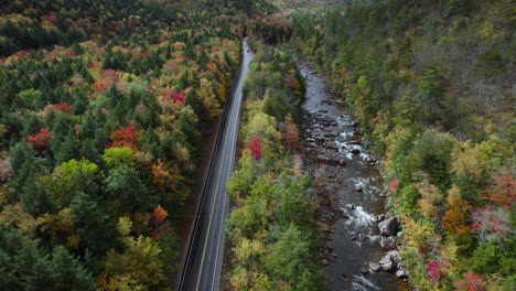 Aerial-view-of-Kancamagus-highway-near-rocky-river-during-colorful-fall