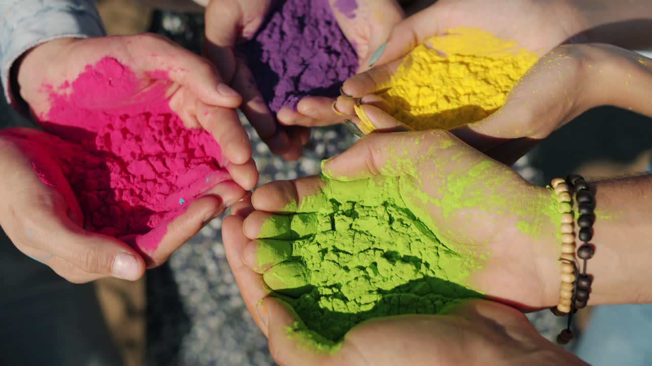Primo piano di mani umane che tengono vernice in polvere colorata gulal per la cerimonia del festival Holi all'aperto