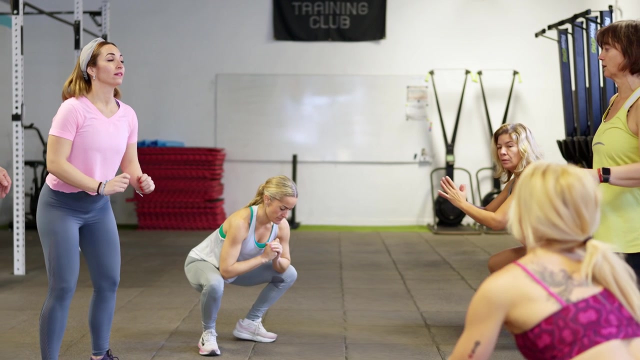 Gruppo di persone che eseguono squat durante una lezione di fitness in palestra