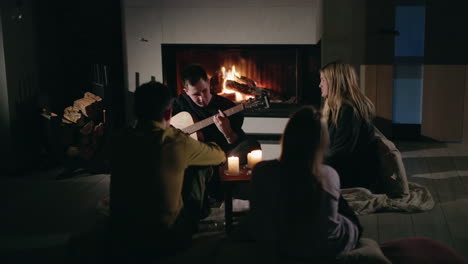 friends gather around fireplace playing guitar