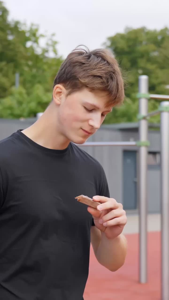 젊은 운동선수가 훈련 쉬는 시간에 단백질 바를 먹고 있어요