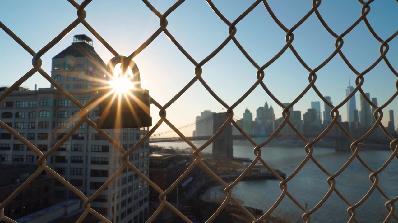 Lucchetto su una recinzione con vista verso il Ponte di Brooklyn e bagliore solare