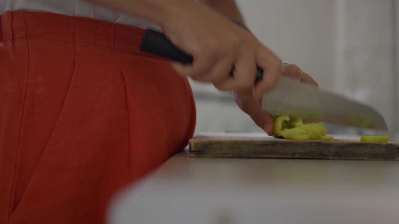 estático, primer plano de una mujer cortando un pimienta verde con un cuchillo de chef