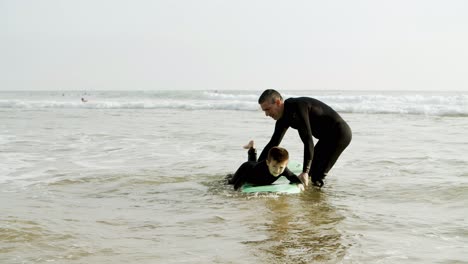 father teaching son surfing in ocean