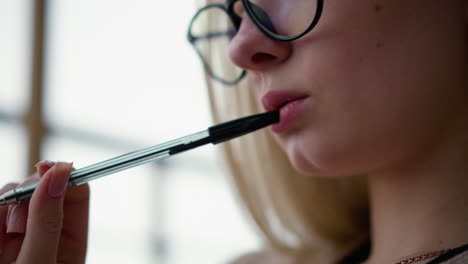 primer plano de una mujer joven girando el bolígrafo suavemente en los labios, profundamente pensativa, contemplativa, pausa intelectual, enfoque creativo, momento de reflexión, reflexión sobre ideas