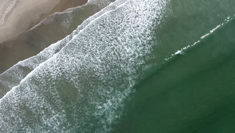 Drone-top-view-shot-of-the-sea-waves-next-to-the-shore