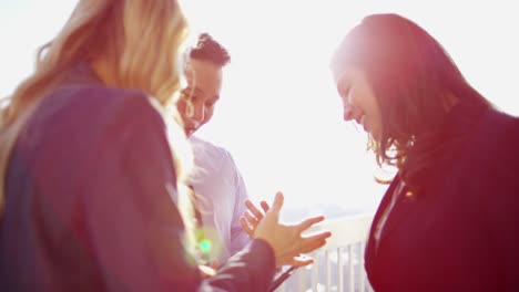 multi ethnic business executives using tablet on rooftop