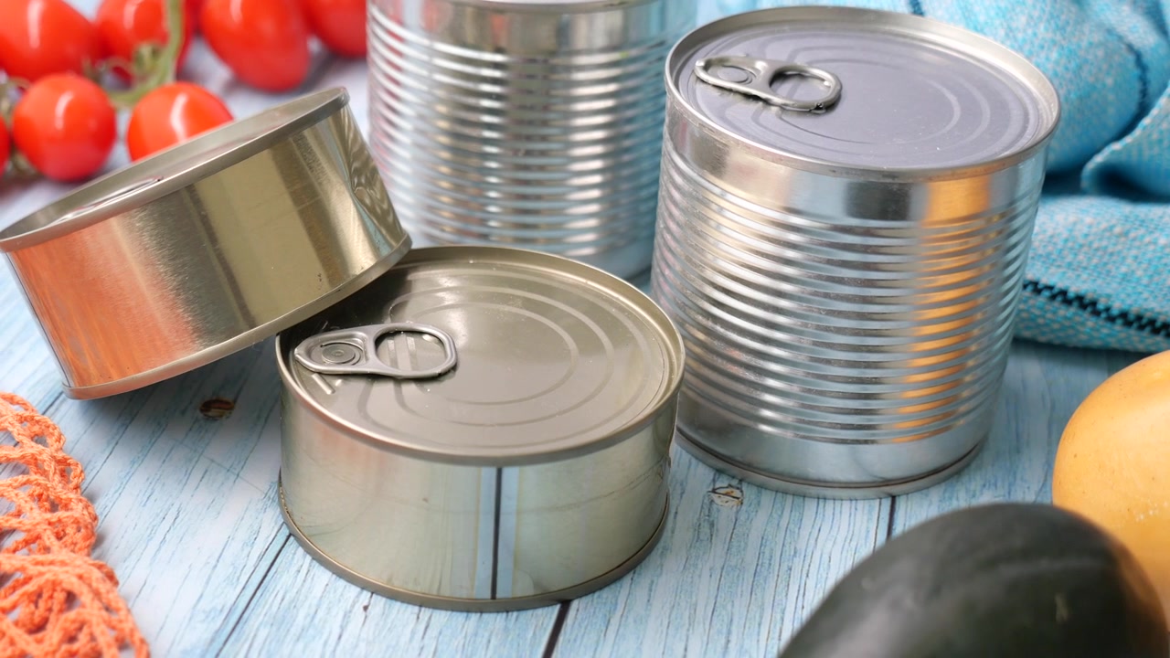 Surtido de latas de metal y verduras frescas sobre una mesa de madera