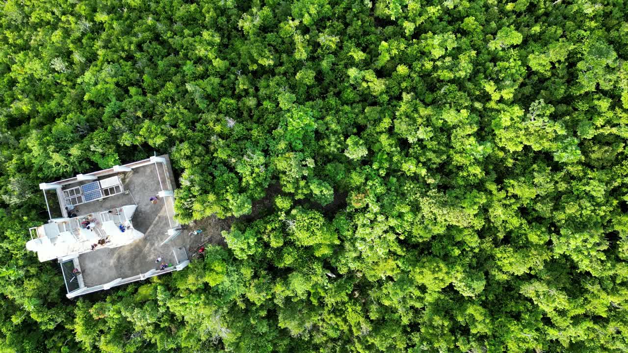impresionante vista aérea de arriba hacia abajo de la exuberante selva tropical en la cima de la montaña con turistas explorando el idílico faro blanco