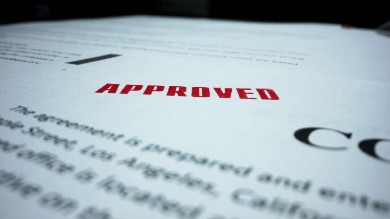 Rubber stamp making seal on contract. Red stamp with text approved on document