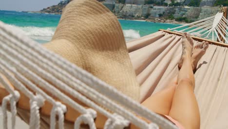 Rear-view-of-Caucasian-woman-relaxing-in-a-hammock-at-beach-4k