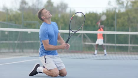 caucasian male tennis player reacts to losing against happy diverse opponent on court in slow motion