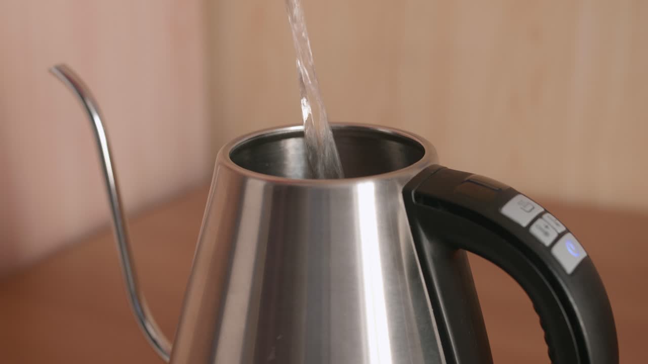 Riempire un bollitore elettrico con acqua versando il liquido nell'oggetto