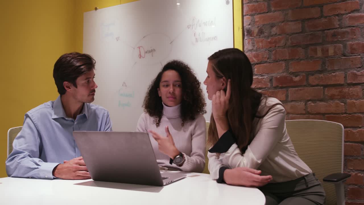 Professionisti creativi che discutono su un portatile in un ufficio moderno.