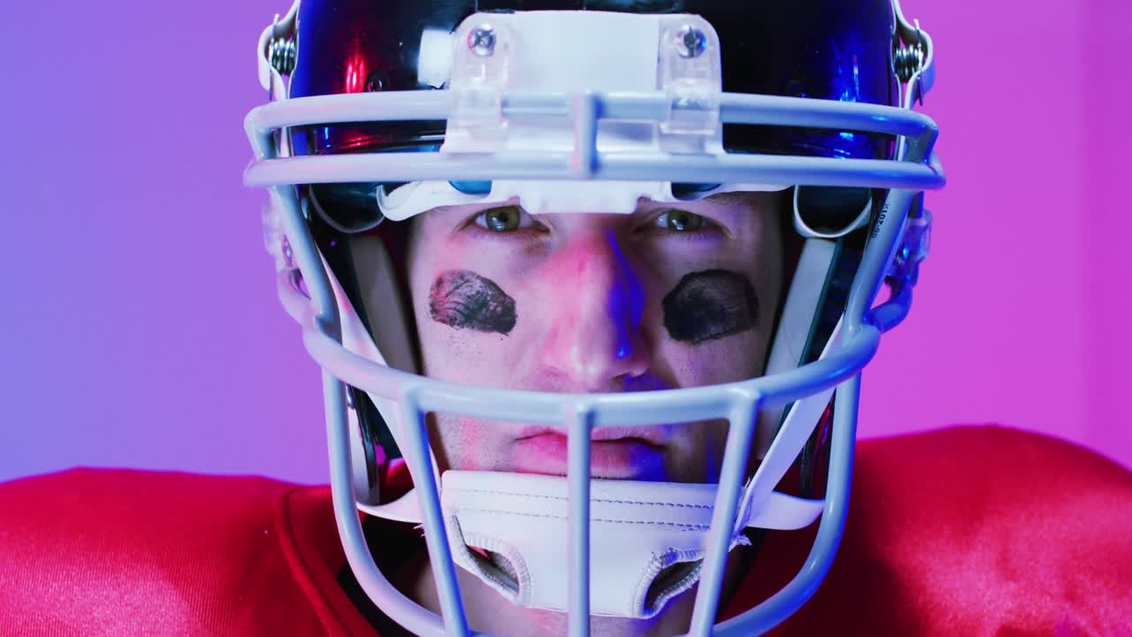 Video ritratto di un giocatore di football americano caucasico con casco su sfondo viola neon