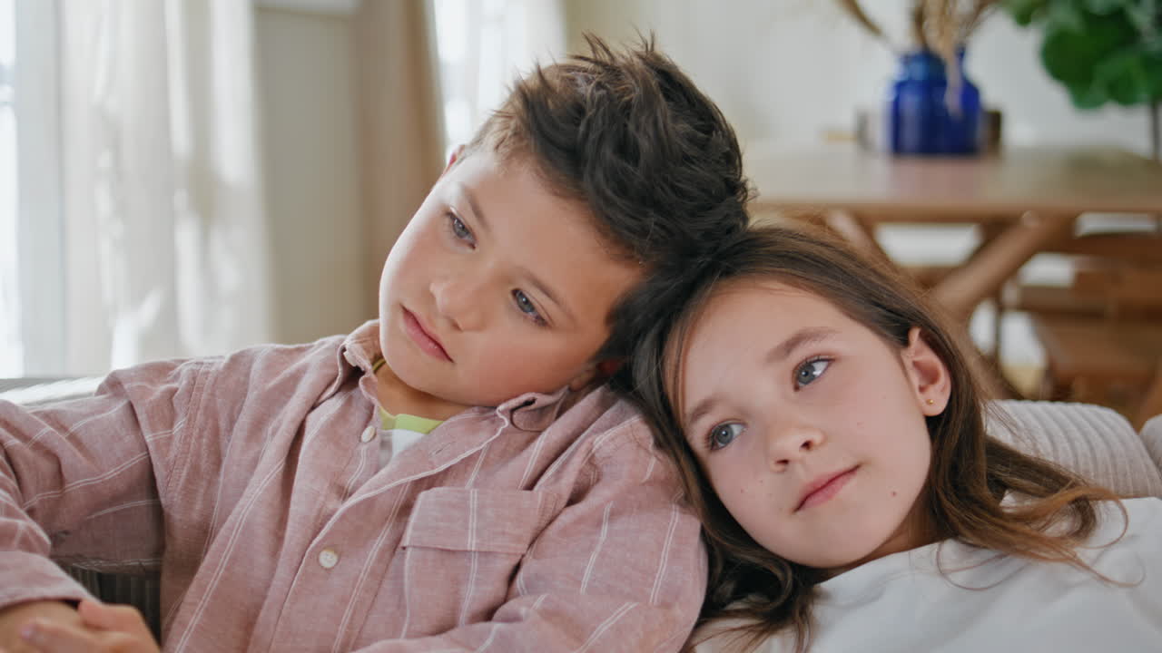 Closeup relaxed kids embracing at cozy couch. Small children watching movie