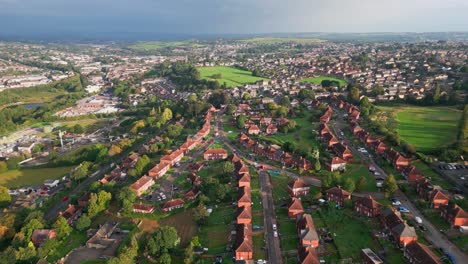 UK-urban-housing:-Aerial-drone-footage-of-Yorkshire's-red-brick-council-estate,-bathed-in-the-morning-sun,-with-homes-and-residents-in-the-streets