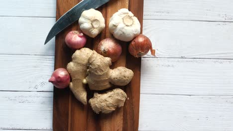 cutlery with garlic, ginger, and onions on a cutting board