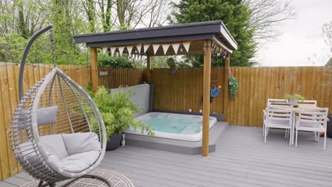 Minimalistic-UK-summer-garden-with-hot-tub,-swing-chair-decking-and-sun-lounger