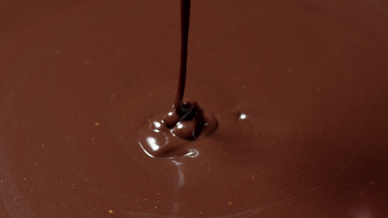 mezcla, agita el chocolate oscuro líquido derretido con batido, el confitero prepara el postre, la cubierta