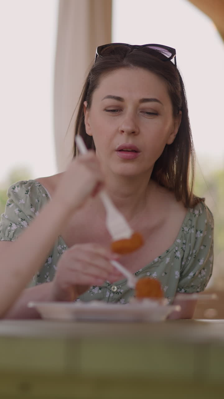 Mother and little girl eat delicious cottage cheese pancakes in resort restaurant closeup slow motion. Dessert of healthy ingredients. Cafe menu