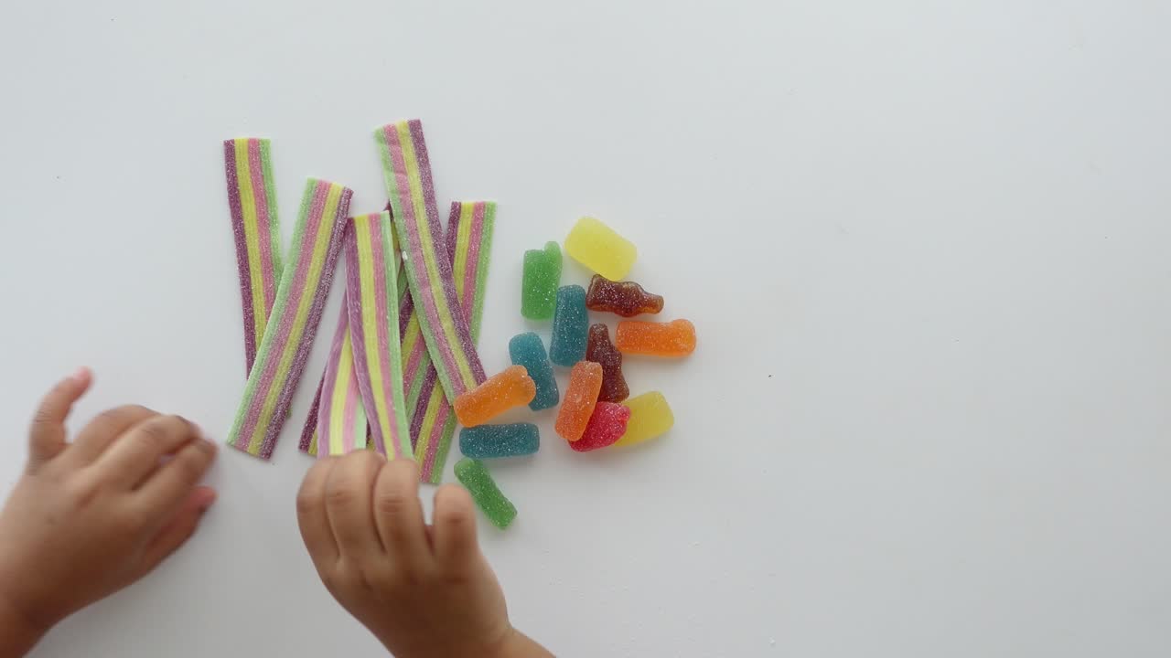 la mano de un niño alcanzando caramelos de goma de colores