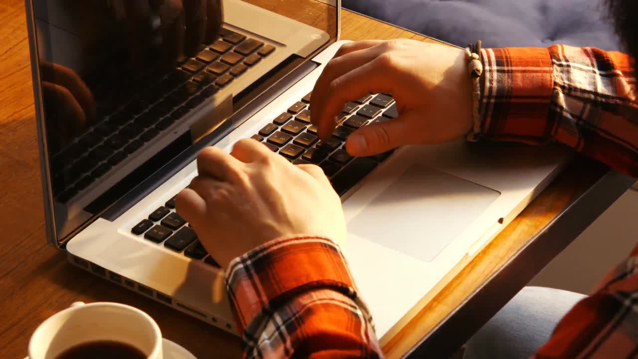 hombre usando una computadora portátil y tomando café