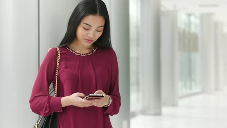 Zeitlupe-Einer-Asiatischen-Frau,-Die-SMS-Schreibt-Und-Verträumt-Nach-Oben-Schaut,-Dann-Wieder-SMS-Schreibt-Und-Dann-Wieder-Nach-Oben-Schaut