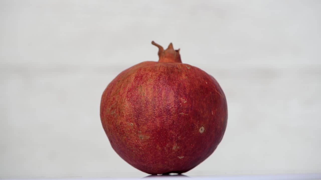 Hel rød granatæblefrugt snurrende på hvid